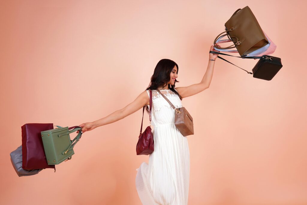 Elegant fashion model holding multiple designer handbags in a vibrant studio setting.